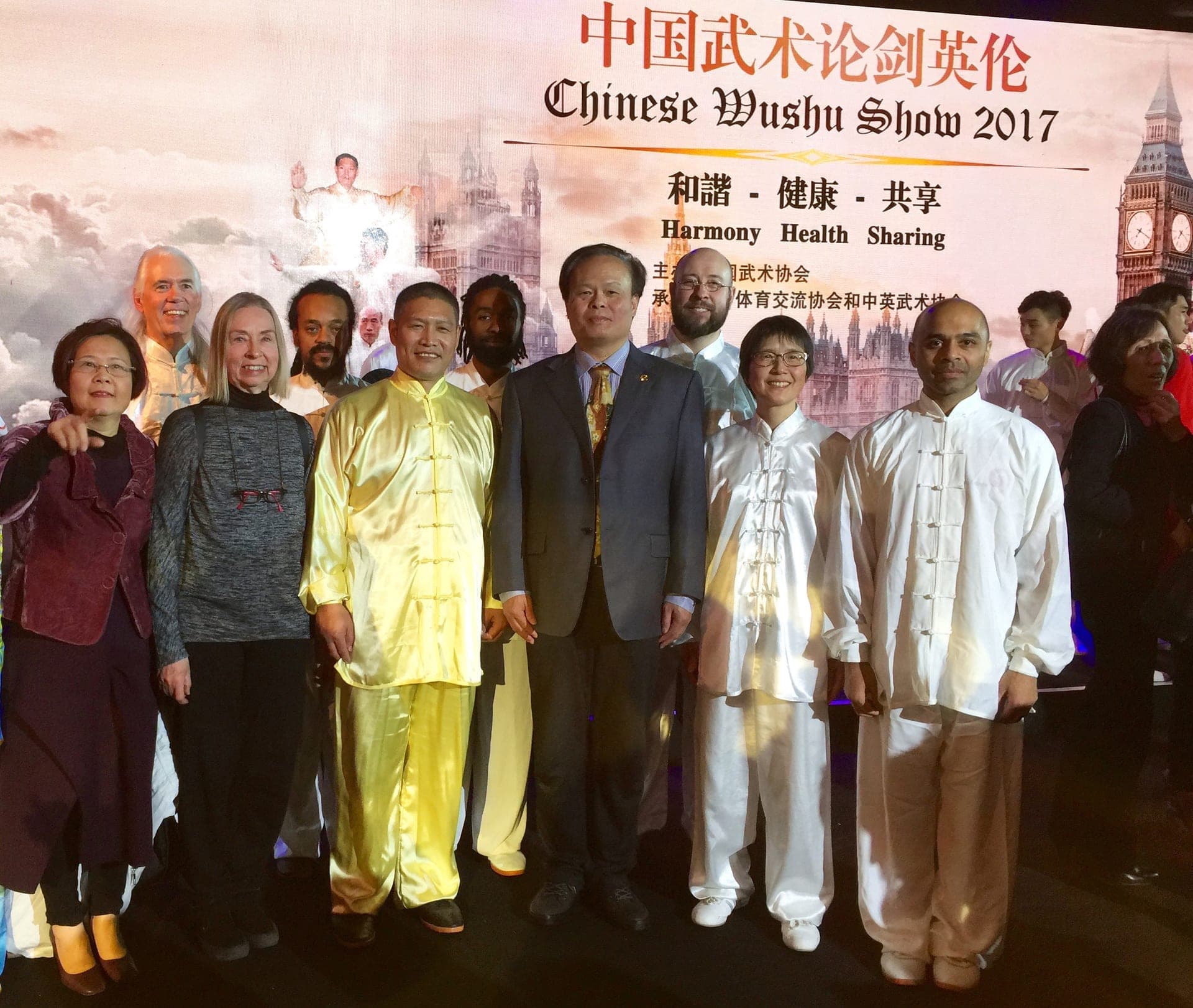 Shifu Liu in yellow silk and Chen Entang in a suit stand on stage with Tai Ji Circle performers in front of a Chinese Wushu Show 2017 backdrop