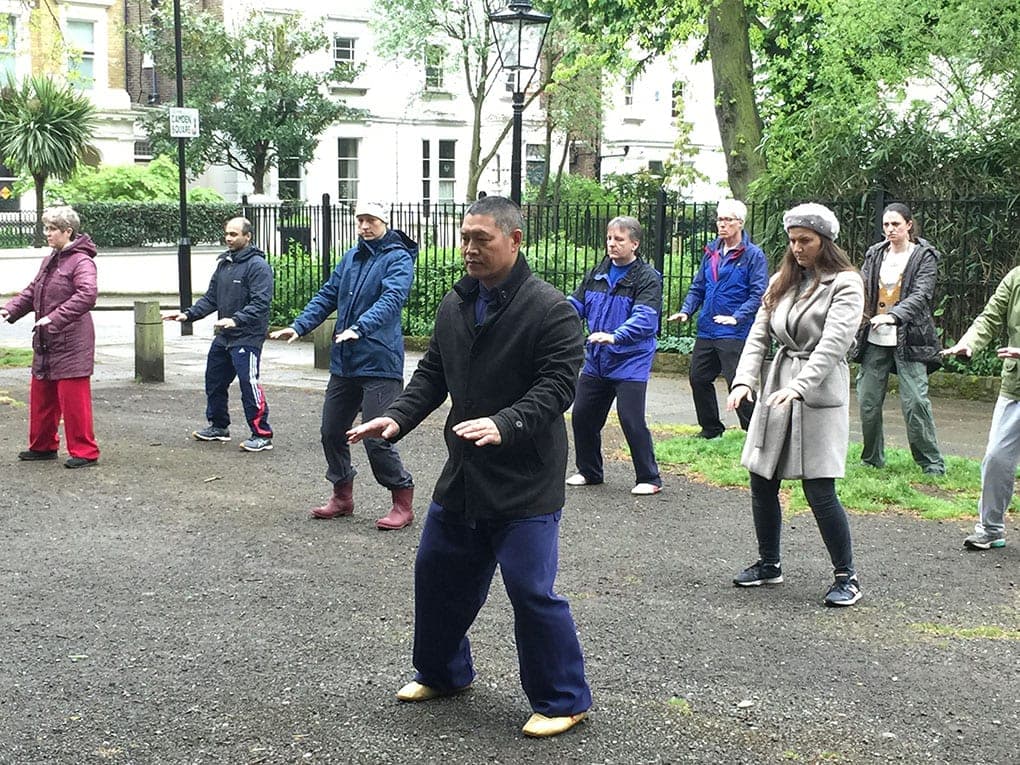 Shifu Liu leads a group through the form in front of the railings of Camden Square