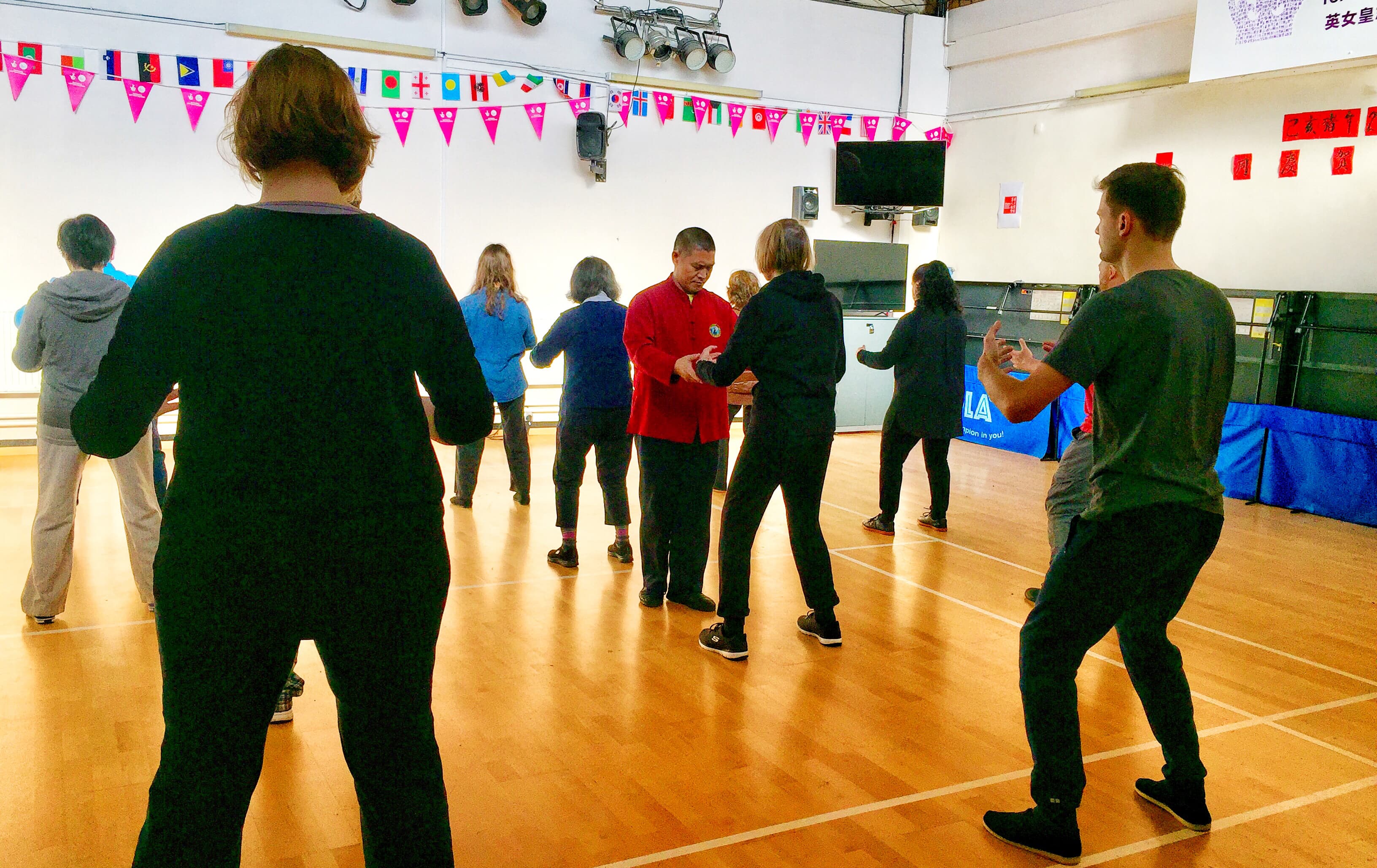 Master Liu in a red jacket correcting a student in a Foundation class