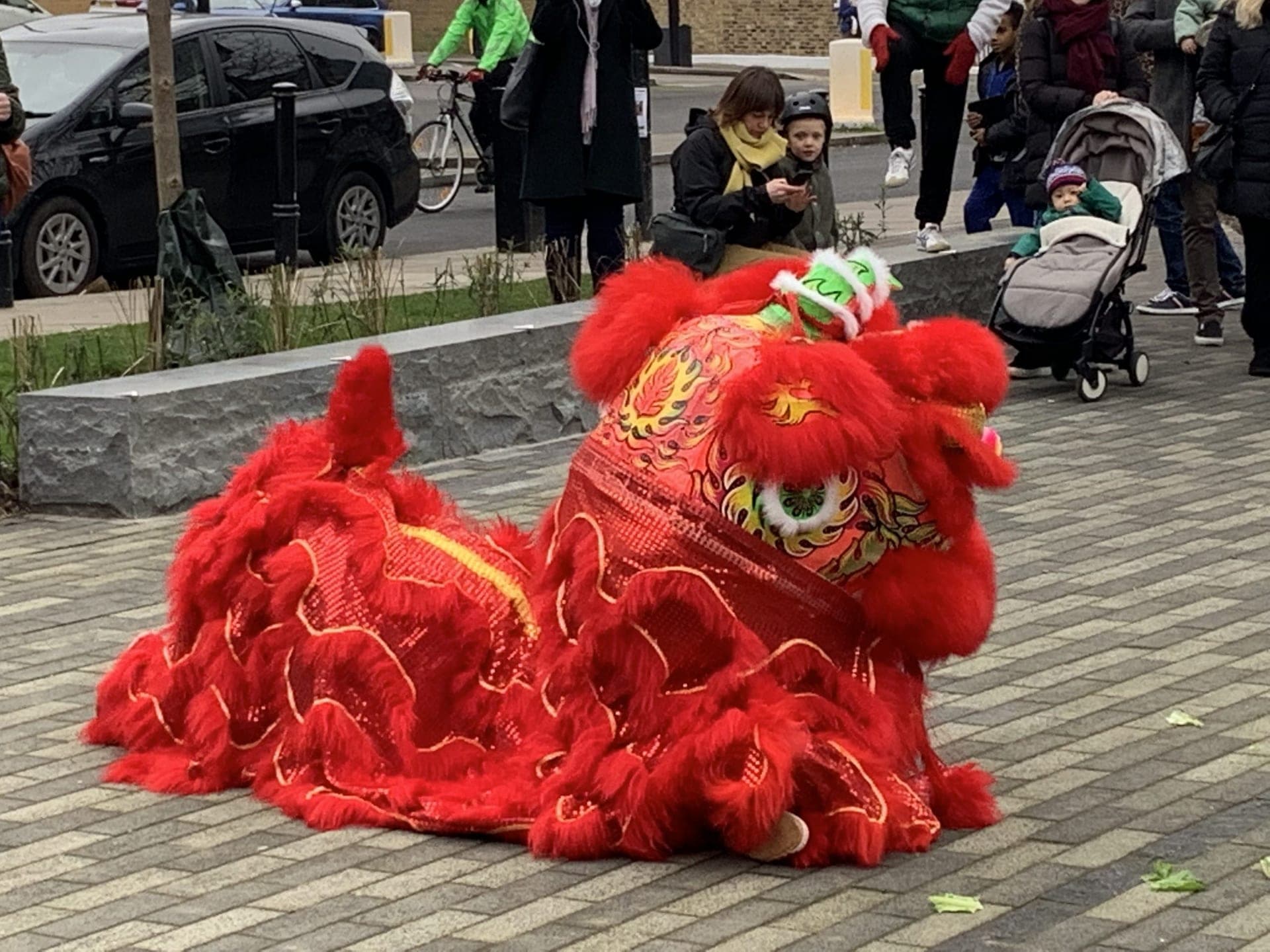 The red lion crouching on the paving as families with pushchairs watch