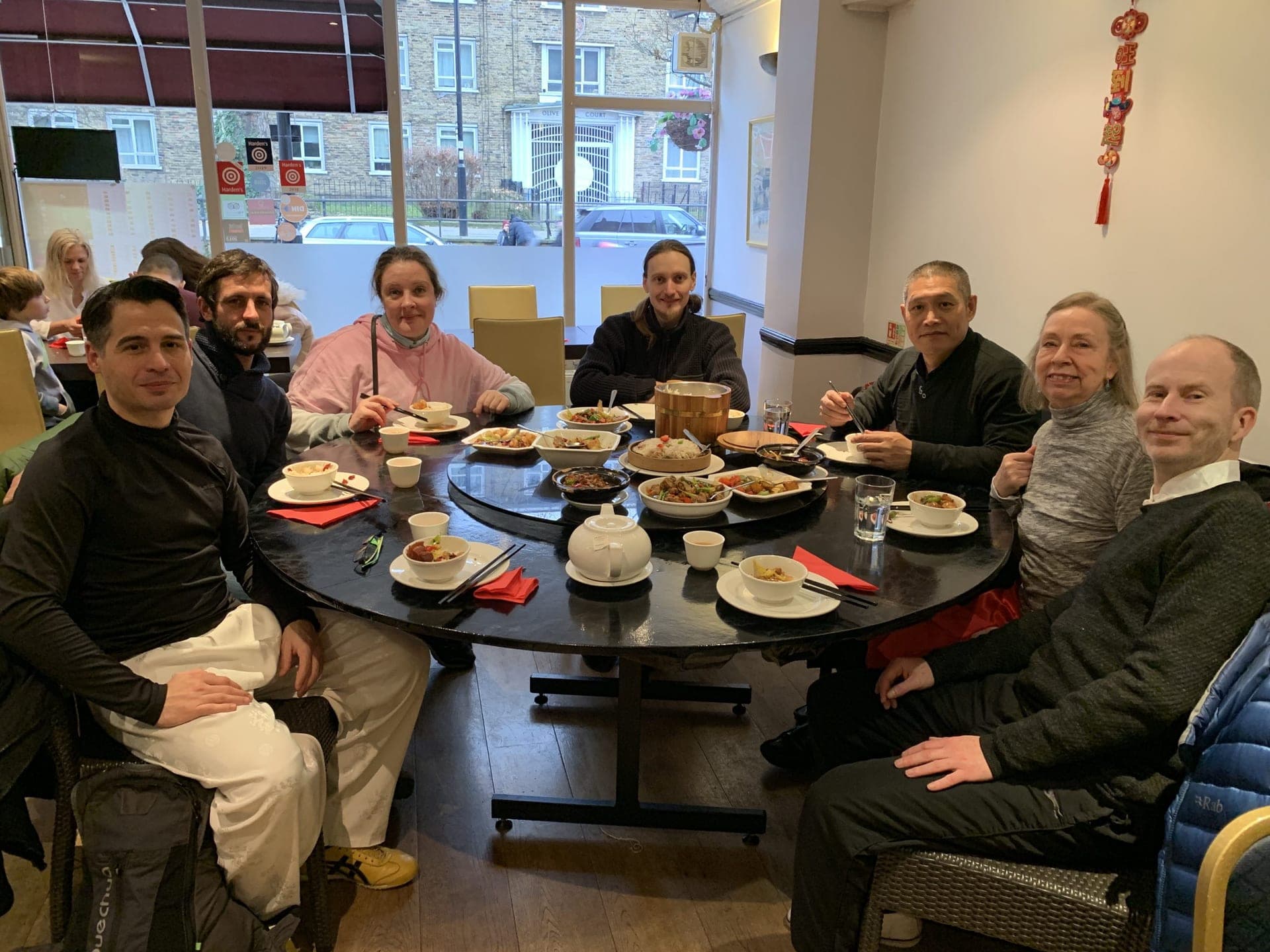 Students and friends smiling round a restaurant table laid with Chinese dishes