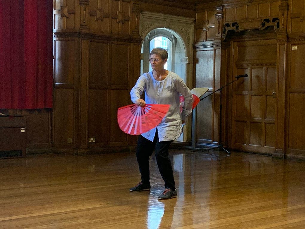 Eva Koskuba performing with a red fan in Oxford Town Hall