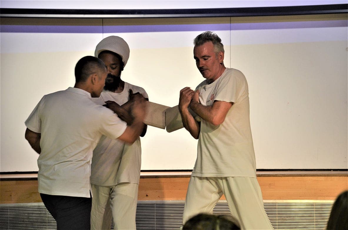 Shifu Liu Quanjun strikes a concrete slab held up by two men on stage