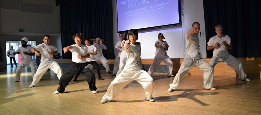 Tai Ji Circle students in white demonstrating the long form on stage in London