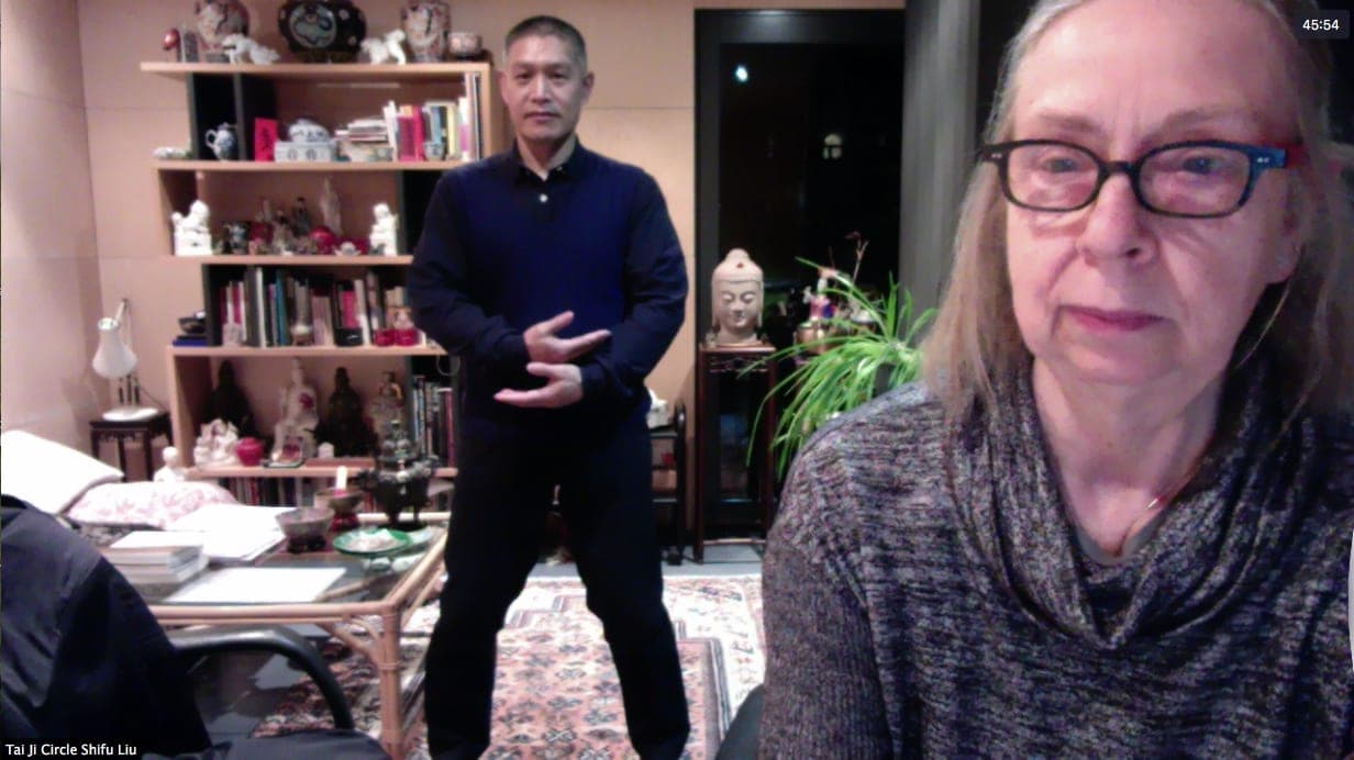 Shifu Liu Quanjun demonstrating on an early Zoom test call, in a room lined with books and Chinese ornaments, with the call's host in the foreground