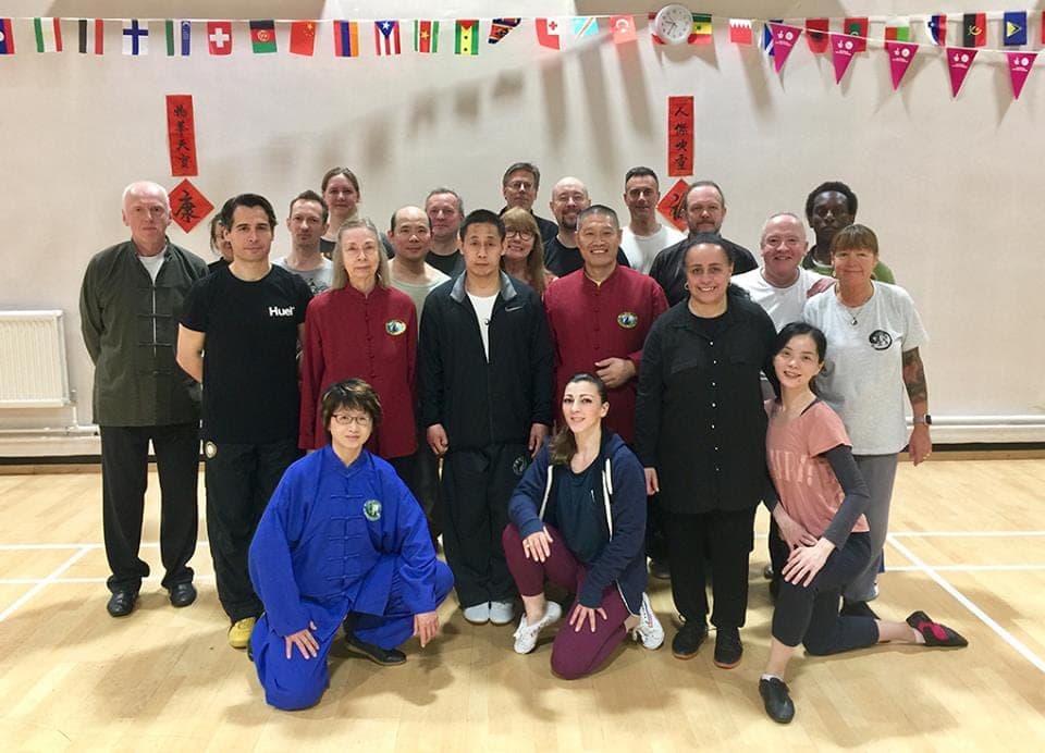 Group photo of the Dajia Yilu workshop, some standing and some kneeling in front, under flag bunting
