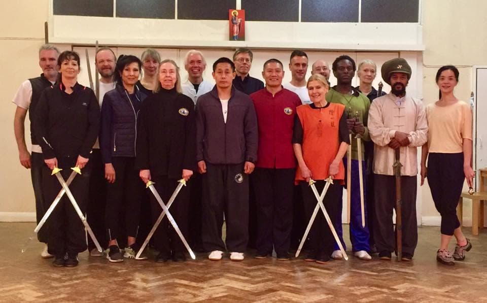 Group photo of the double swords workshop, crossed swords held in front of the front row
