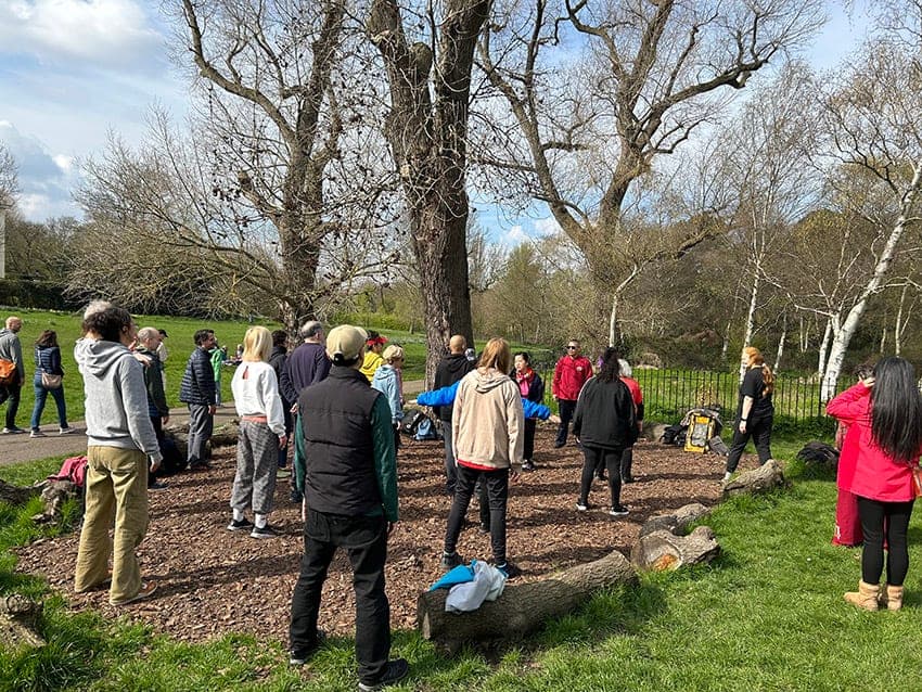 Students standing in a circle among trees during a free class in the park