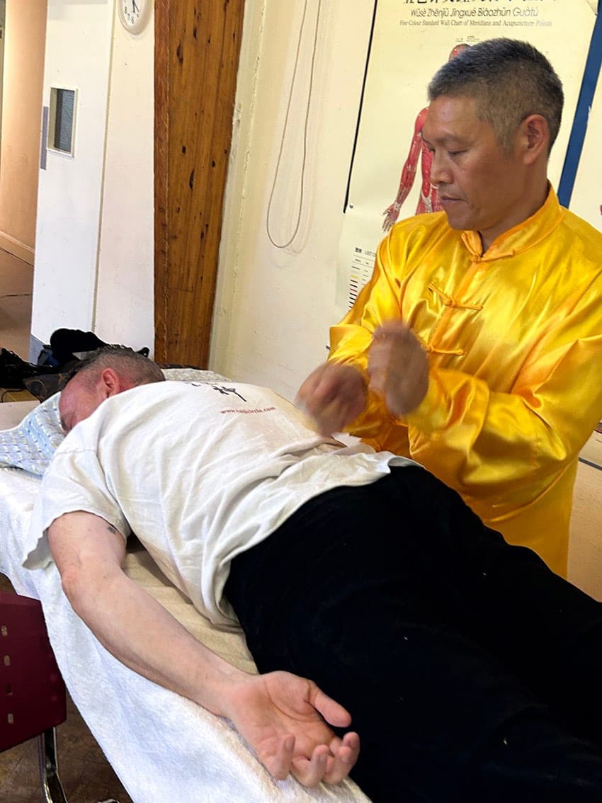 Shifu Liu demonstrating tui na Chinese massage on a student lying on a treatment couch