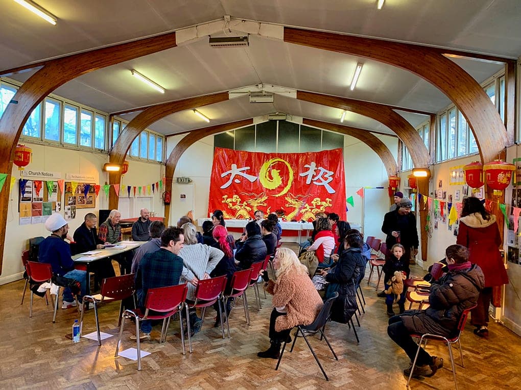 Students gather on chairs for the 2019 AGM in front of a large red Taiji banner