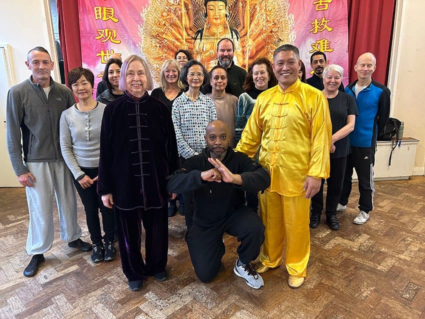 Shifu Liu, in yellow silk, with Chris Jones and a group of students celebrating Christmas in a hall, December 2023