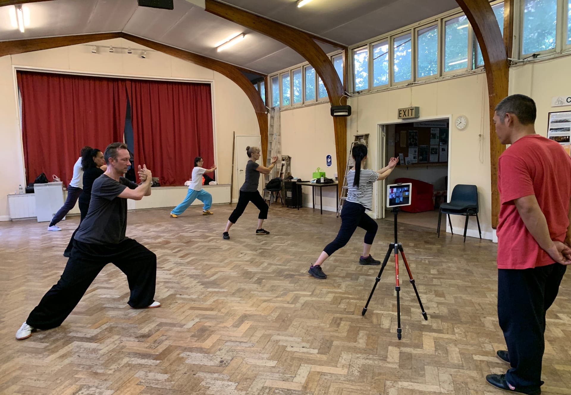 A spaced-out Taiji class in a church hall, with an iPad on a tripod streaming it to students on Zoom