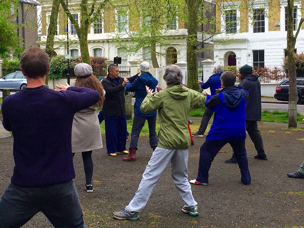 Participants practise the form in the square, with Shifu Liu among them